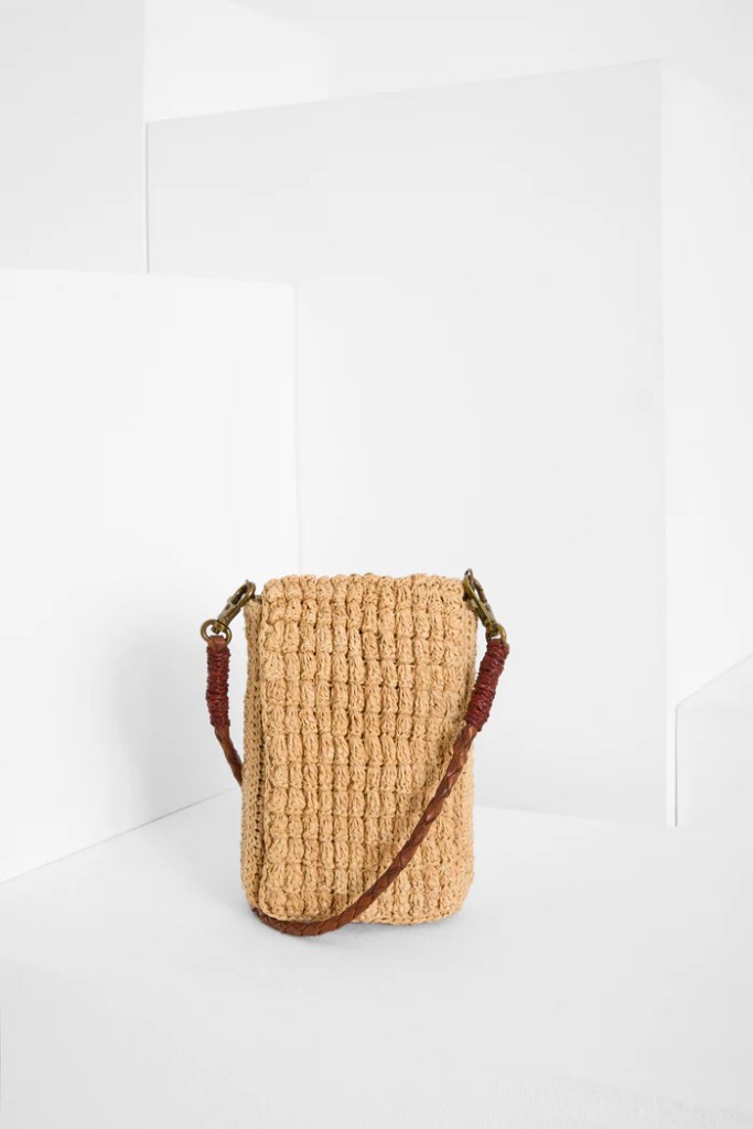 Die von Hand gefertigte Handytasche VAO von IBELIV besteht aus Raphia. Sie hat einen abnehmbaren Riemen aus geflochtenem Leder, mit dem sie über die Schulter getragen werden kann.