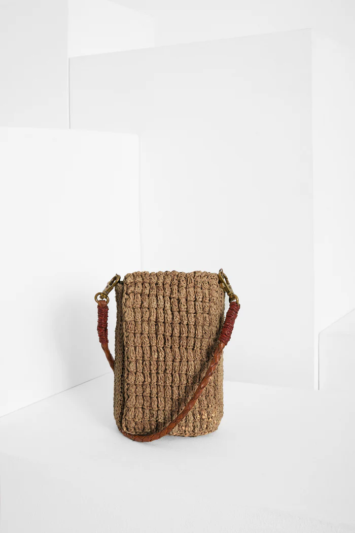 Die von Hand gefertigte Handytasche VAO von IBELIV besteht aus Raphia. Sie hat einen abnehmbaren Riemen aus geflochtenem Leder, mit dem sie über die Schulter getragen werden kann.